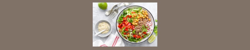 How To Safely Transition To A Plant-Based Diet (1).

Medium gray background, white square in center, a plant based meal  ( chick peas, vegetables ...in a white bowl, a lime, white bowl, white napkin, silverware. 